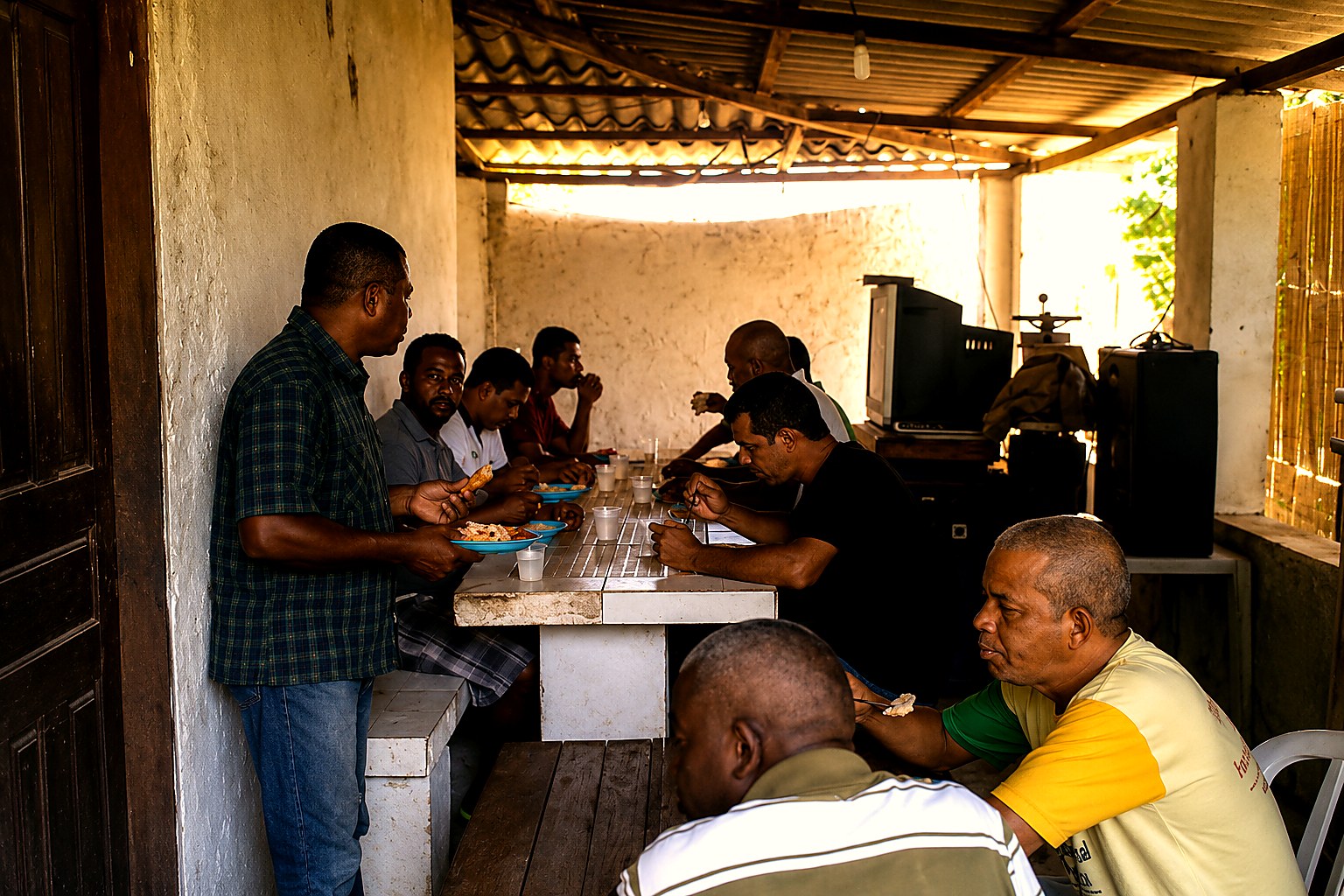 Homens reunidos em refeição comunitária no Instituto